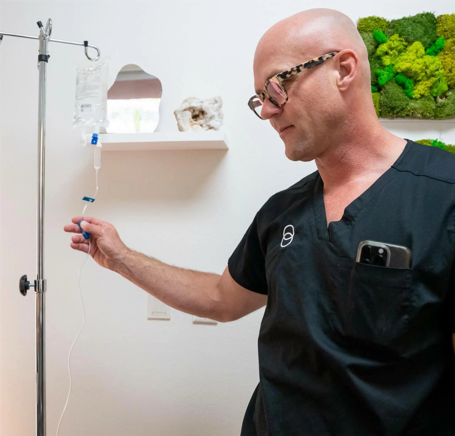 Dr. How in black scrubs wearing glasses touch an IV line